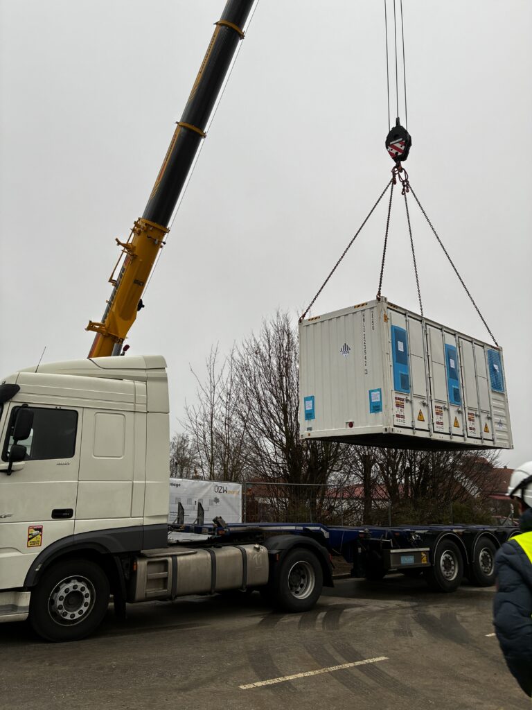 Der Kran hebt einen Cotainer mit einem der ÜZW Batteriespeicher vom LKW.