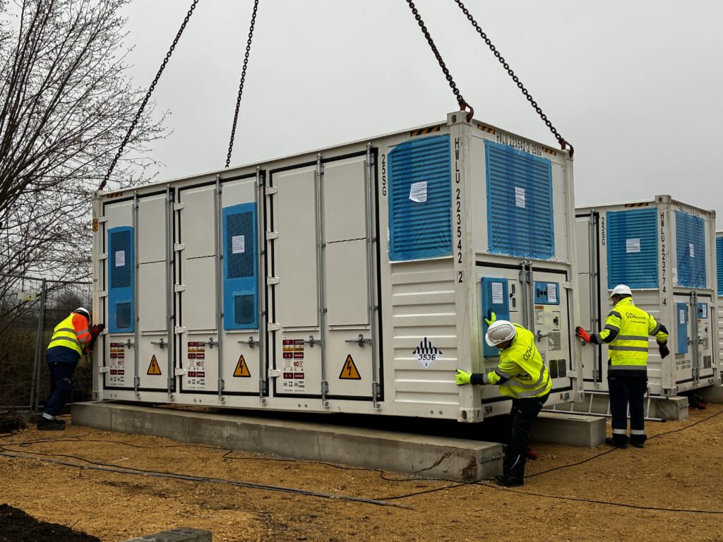 Per Kran wird der vierte Container mit einem ÜZW Batteriegroßspeicher auf das Fundament gestellt.